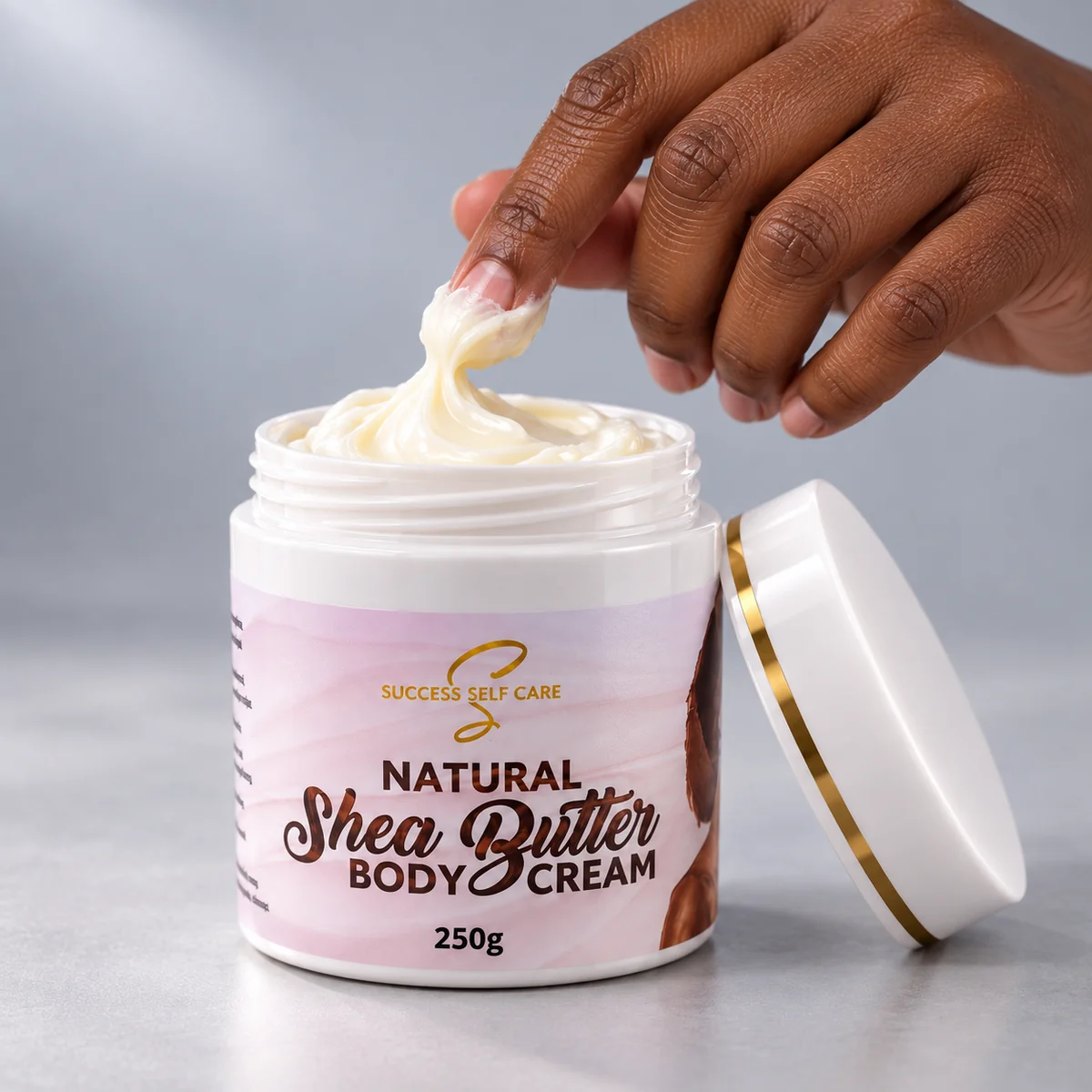 Fingers scooping Success Self Care Whipped Shea Butter Body Cream from an open 250g jar